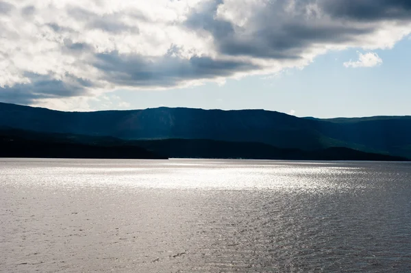 Niedrige dunkle Wolken über beleuchtetem Wasser an der Steilküste — Stockfoto