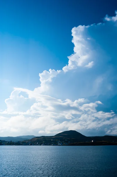 Büyük billowing bulutların üzerinde kıyı köyü