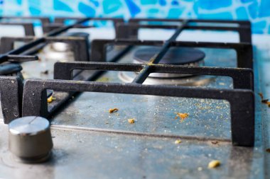 Kirli gaz ocağının tepesinde yemek artıkları var. Yağ lekeli kirli çelik mutfak ocağı. Bahar temizliği, eski mutfak yağ lekelerini, kızartma lekelerini, yağ lekelerini ve yanmış parçaları çıkarın.