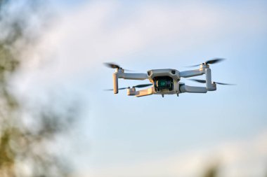 Gökyüzünde bir kuadkopter drone var. Küçük İHA gökyüzünde uçup video ve fotoğraf çekiyor. Uzaktan kumandalı hava dağıtımı ve casus.
