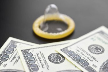 Prezervatif ve banknot. Fuhuş konsepti. Doğum kontrol hapı olan bir Amerikan doları. Gecelik seks için para öde. Fahişelik ve fahişelik..