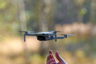 Kuadkopter drone operatör elinde. Video ve fotoğraf çektikten sonra insansız hava aracı yere indi. Uzaktan kumandalı hava dağıtımı ve casus.