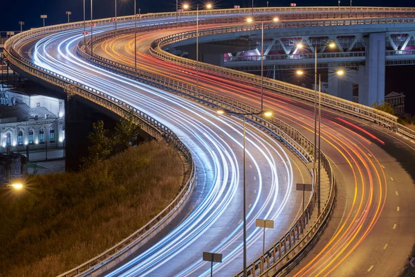 Highway at night lights. Fast car light path, trails and streaks on interchange bridge road. Night light painting stripes. Long exposure photography