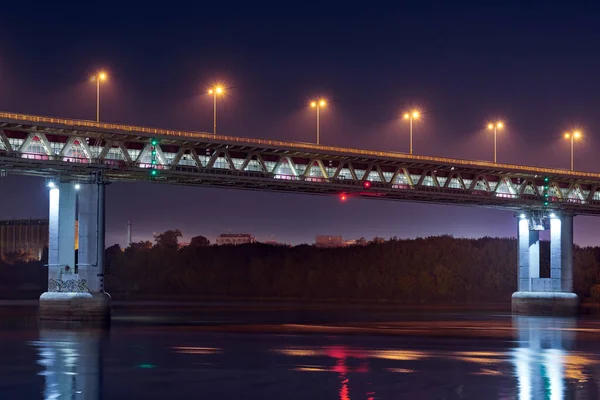 Night city bridge lighting. Beautiful reflection of night lights on water surface. Long exposure photography.