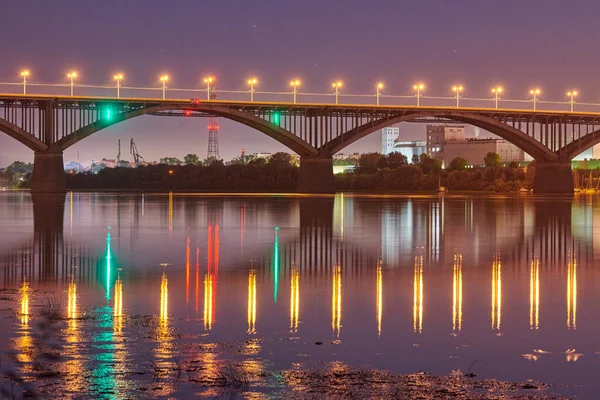 Night city bridge lighting. Beautiful reflection of night lights on water surface. Long exposure photography.