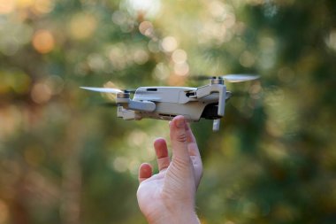 Kuadkopter drone operatör elinde. Video ve fotoğraf çektikten sonra insansız hava aracı yere indi. Uzaktan kumandalı hava dağıtımı ve casus.