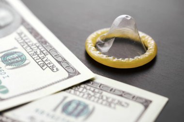 Prezervatif ve Amerikan doları. Fuhuş konsepti. Gecelik seks için para öde. Fahişelik ve fahişelik. Gebelik önleyicili masada Amerikan Doları parası.