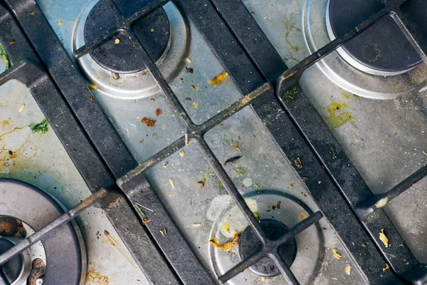 Dirty gas stove top with food leftovers. Unclean steel kitchen cooktop with greasy spots. Spring-cleaning, remove kitchen old fat stains, fry spots, oil splatters and burned-on bits