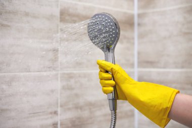 Kadın eli koruyucu sarı lastik eldiven tutuyor. İç banyoda su dökülüyor. Kopya alanı, hareket bulanıklığı..