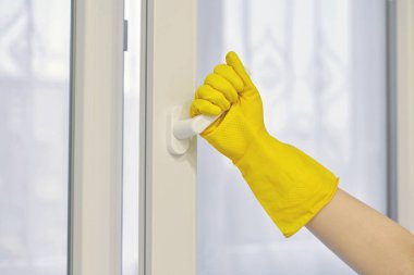Koruyucu sarı lastik eldiven, plastik pencereyi açar ve kapatır. Temizlik, bakım ve onarım.