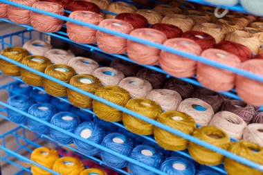 Örgü ve dikiş işi için raflardaki yün yumakları veya iplikler. Kumaş mağazasındaki tuhafiyeciler için aksesuarlar. Renkli resim, arkaplan.