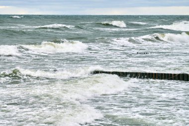 Köpüklü mavi denizin manzarası. Baltık Denizi manzarası denize kadar uzanan eski, uzun, ahşap dalgalar. Sessizlik, yalnızlık, sakinlik ve huzur..