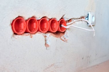 Yeni elektrik tesisatı, plastik soket kutuları ve gelecekteki prizler için elektrik kabloları alçılı duvarda, ev yenileme konsepti.