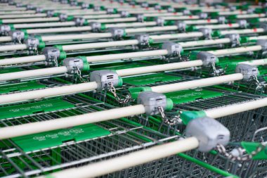 Süpermarkette sıra sıra park edilmiş yük arabaları. Birçok boş yeşil alışveriş arabaları sırada.