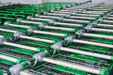Birçok boş yeşil alışveriş arabaları sırada. Süpermarkette park halindeki yük arabaları..