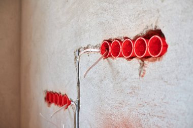 Yeni elektrik tesisatı, plastik soket kutuları ve gelecekteki prizler için elektrik kabloları alçılı duvarda, ev yenileme konsepti.