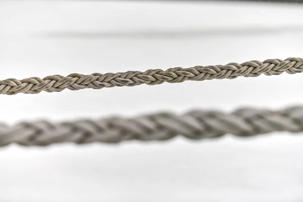 Two sail ropes hanging from fishing ship or yacht, close up. Detailed fragment of rope.