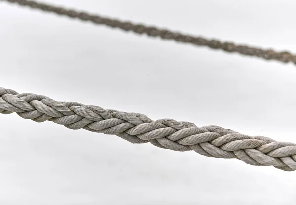 Two sail ropes hanging from fishing ship or yacht, close up. Detailed fragment of rope.