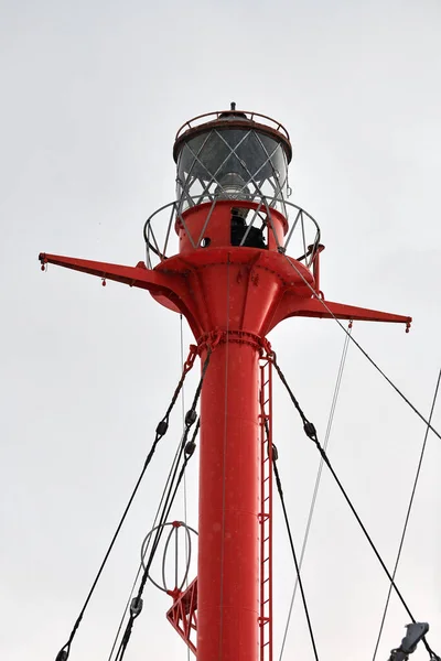 Fragment of mast and signal lamp of floating beacon, close up. Sailing mast of ship on cloudy sky background. Vessel main mast.