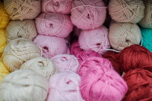 Close up of multicolored yarn balls in knitting shop center. A lot of color yarn for knitting. Colorful yarn wool on shopfront, macro.