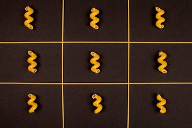 İtalyan makarnası, siyah arka plan. Metin için tasarım. Geleneksel pişmemiş spagetti ve cavatappi, spirali.