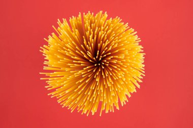 Bir demet çiğ makarna, üst manzara, kırmızı arka plan. Makarnayı kapat, yukarıdan bak..