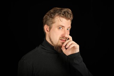 Komik sakallı adam burnunu karıştırıyor, siyah arka plan. Siyah polo yakalı genç adam. Aptal, aptal adam..