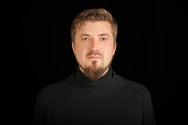 Sevimli sakallı adam, siyah arkaplan. Siyah polo yakalı genç adam. Kendinden emin, başarılı bir adam..