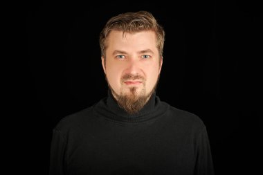 Sevimli sakallı adam, siyah arkaplan. Siyah polo yakalı genç adam. Kendinden emin, başarılı bir adam..