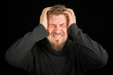 Yorgun sakallı adam portresi, baş ağrısı, siyah arkaplan. Aşırı çalışma, baş ağrısı konsepti. Siyah polo yakalı genç adam. Öfkeli adamı işaret etmekten yorgun ve bitkin düştüm..