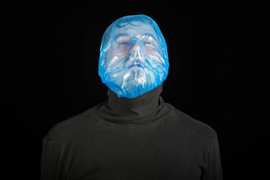 Kafasında intihar torbası var. İntihar için çıkış çantası. Kendini boğma konsepti. Kafasında çöp torbası var. Nefes darlığı, nefes darlığı. Siyah arkaplan.