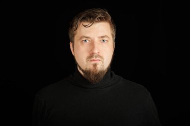 Sevimli sakallı adam, siyah arkaplan. Siyah polo yakalı genç adam. Kendinden emin, başarılı bir adam..