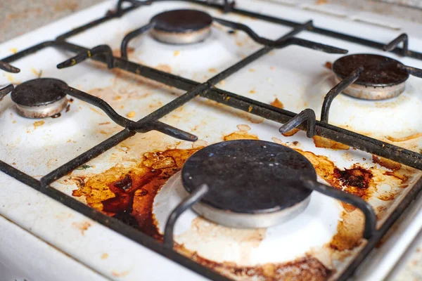 Dirty stove with food leftovers. Unclean gas kitchen cooktop with greasy spots, old fat stains, fry spots and oil splatters.