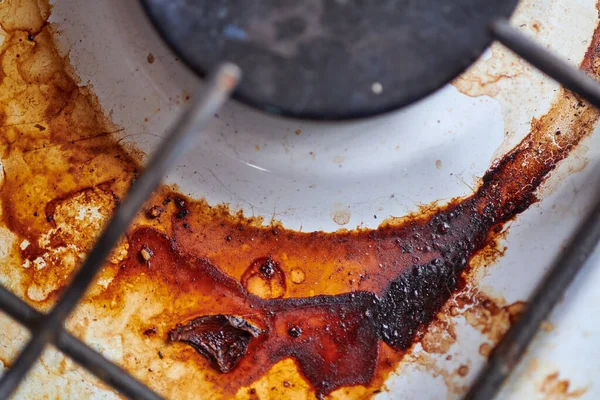 Dirty stove with food leftovers. Unclean gas kitchen cooktop with greasy spots, old fat stains, fry spots and oil splatters.