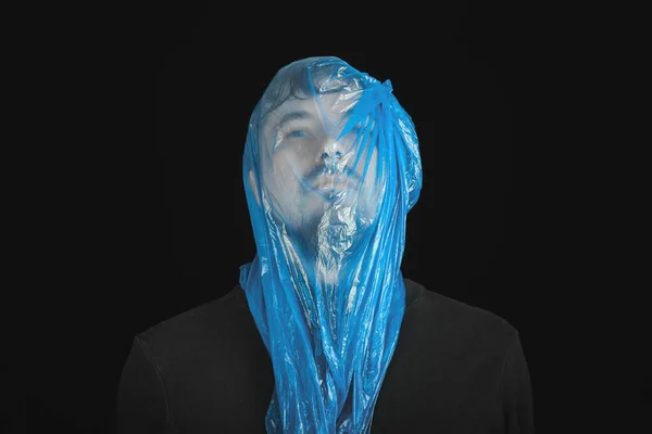 Blue garbage bag on man head. Exit bag for suicide. Self-asphyxiation concept. Suicide bag on man head. Shortness of breath, lack of air. Black background.