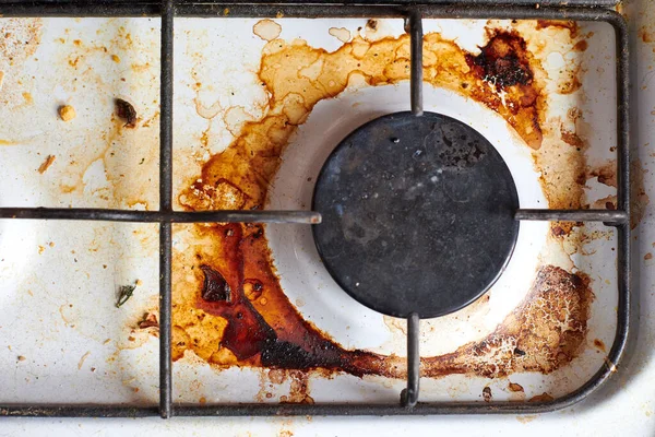 Dirty grease stove with food leftovers. Unclean gas kitchen cooktop with greasy spots, old fat stains, fry spots and oil splatters.