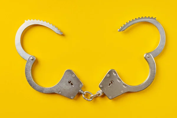 黄色の背景に手錠を開いた 刑務所から解放され自由の概念だ 自由の剥奪 犯罪者の逮捕 — ストック写真