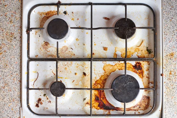 Dirty stove with food leftovers. Unclean gas kitchen cooktop with greasy spots, old fat stains, fry spots and oil splatters.
