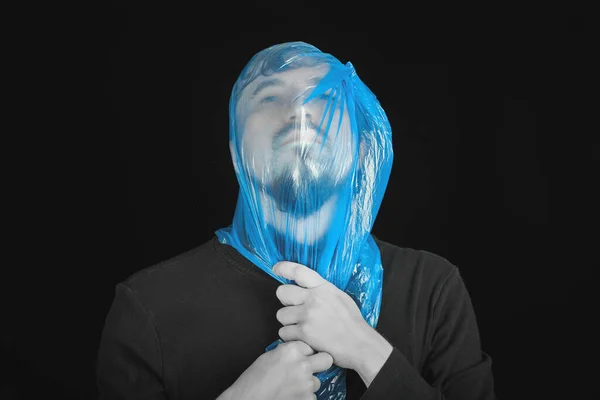 Blue garbage bag on man head. Exit bag for suicide. Self-asphyxiation concept. Suicide bag on man head. Shortness of breath, lack of air. Black background.