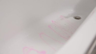 Pembe eldivenler giyen, parlak bir banyoda beyaz küveti ovalayan birinin yakın çekimi. Resim temizlik eylemini ve pürüzsüz yüzeyi yandan yakalar