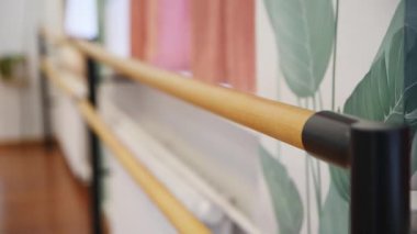 Black Metal 'e bağlı ahşap bale barı yumuşak bir şekilde aydınlatılmış dans stüdyosunun içini destekler. Arkaplanda yeşil yaprak desenli duvar dekorasyonu ve sıcak pembe perdeler var, davetkar bir atmosfer yaratıyorlar.