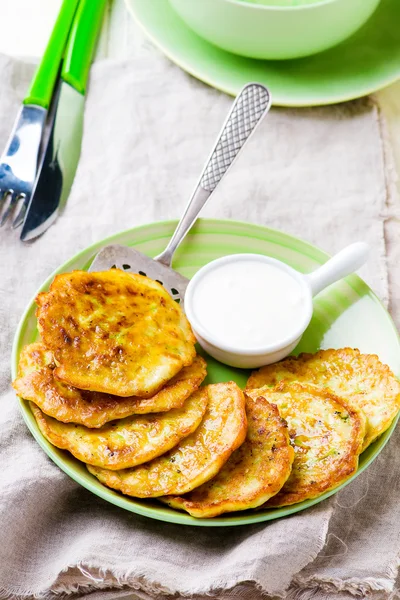 Vegetabiliska squash fritters med gräddfil på en grön platta. — Stockfoto