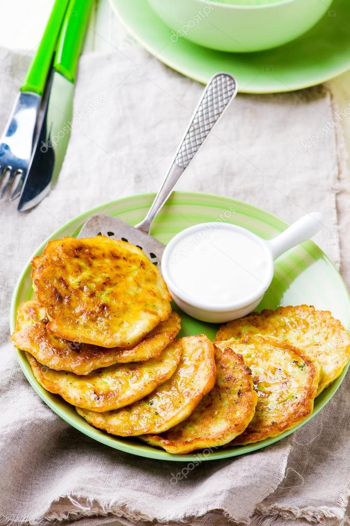 vegetable marrows fritters with sour cream on a green plate. 