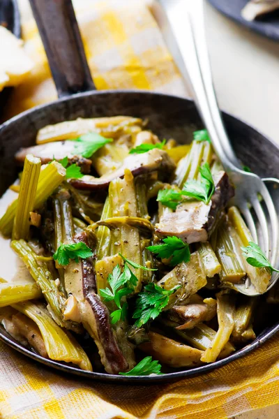 Stewed celery with cepes in a vintage frying pan. — Stock Photo, Image