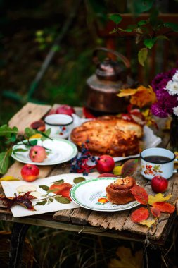 Elmalı çörekler, sonbahar bahçesindeki ahşap bir masada karamel. Koyu kırsal fotoğraf. Seçici odaklanma.