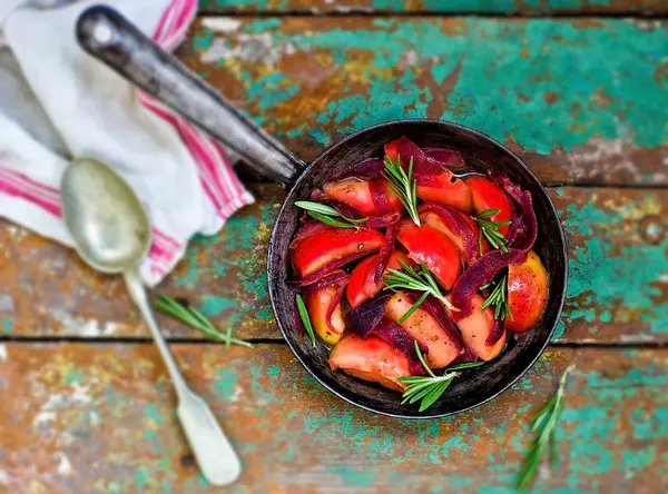 Geschmorte Zwiebeln und Äpfel mit Rosmarin in einer Pfanne — Stockfoto