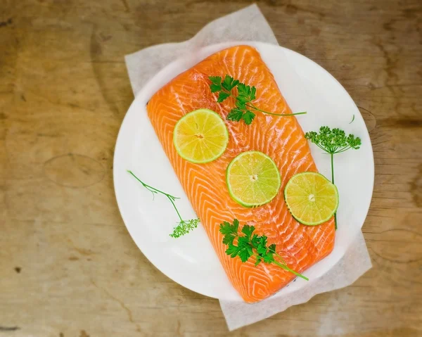 Filet frais et brut d'un saumon avec des tranches de citron vert et de légumes — Photo