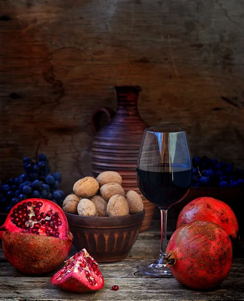 Гранат, грецкие орехи, виноград и вино на деревянном фоне . — стоковое фото
