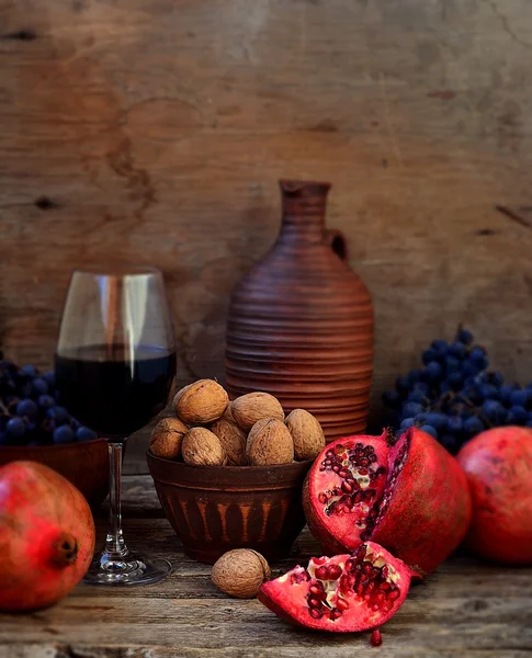 Grenade, noix, raisins et vin sur fond de bois . — Photo