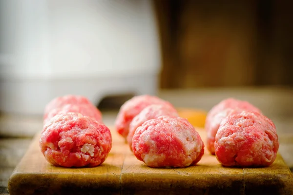 Rått kött bollar på en skärbräda. — Stockfoto